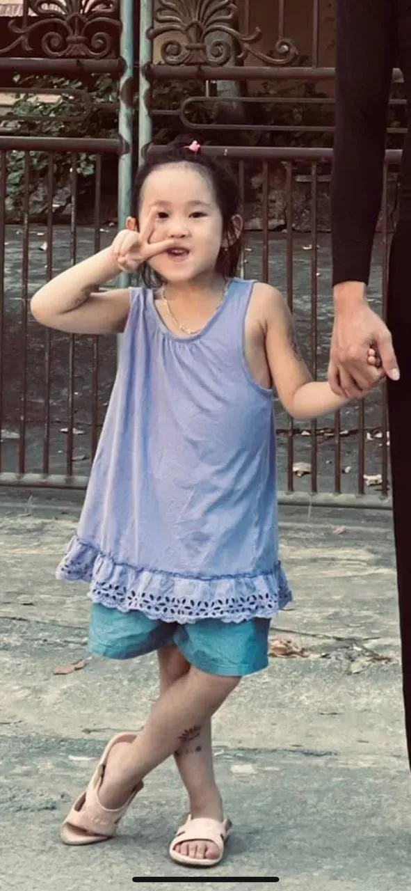 Bé gái nắm tay người lớn trên vỉa hè